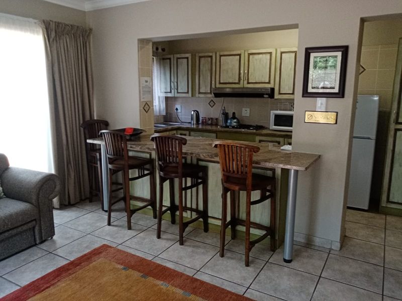 Open plan living area featuring a kitchen with granite breakfast bar, built-in cabinetry, and tiled flooring, seamlessly connecting to the living space.