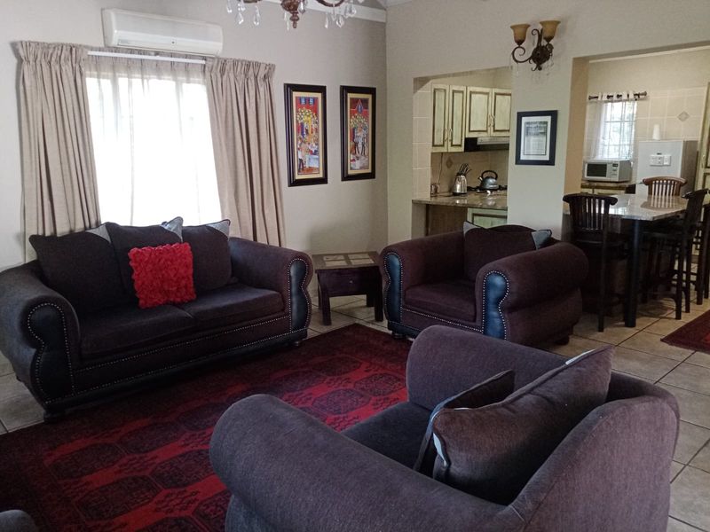 Open-plan living area featuring tiled floors, a split-system air conditioner, and a connected kitchen with granite countertops and breakfast bar seating.