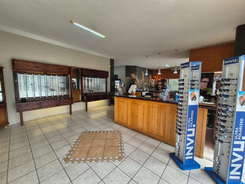 Commercial retail space featuring built-in wooden display cabinetry, a service counter, and tiled flooring, suitable for an optical or boutique retail business.