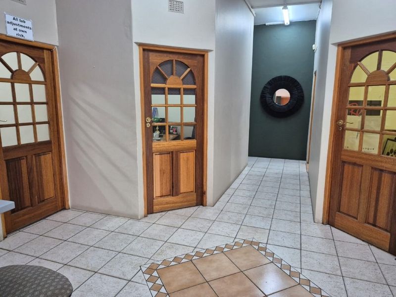 A commercial hallway featuring tiled flooring and multiple wooden panelled doors providing access to various office or workspace units.