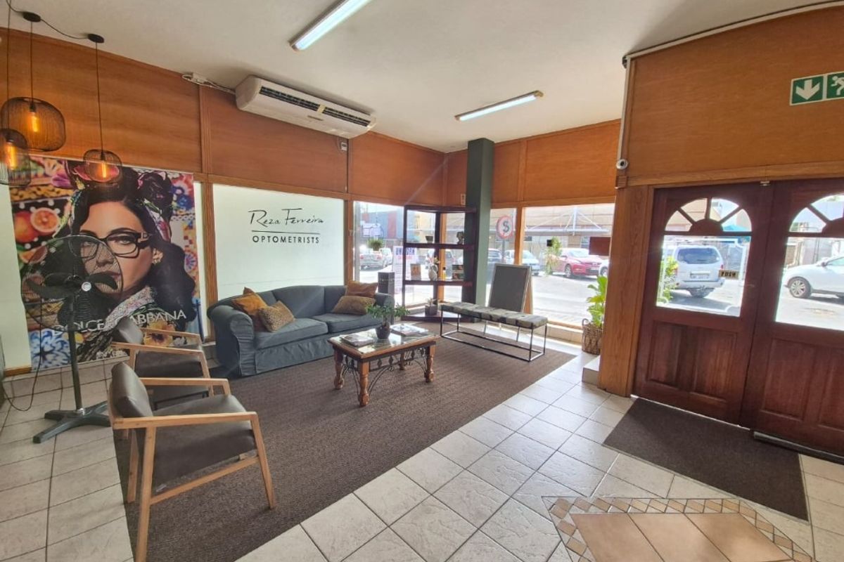 Commercial reception and waiting area featuring timber wall paneling, tiled and carpeted flooring, and large street-facing windows.
