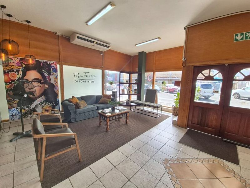 Commercial reception and waiting area featuring timber wall paneling, tiled and carpeted flooring, and large street-facing windows.
