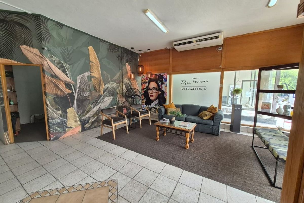 Commercial reception and waiting area featuring tiled flooring, glass storefront entrance, and wall-mounted air conditioning unit.