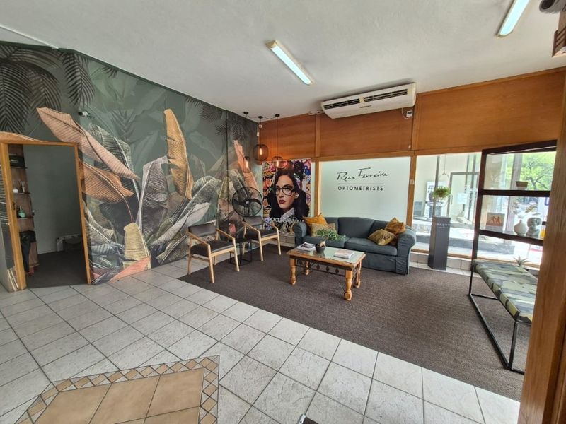 Commercial reception and waiting area featuring tiled flooring, glass storefront entrance, and wall-mounted air conditioning unit.