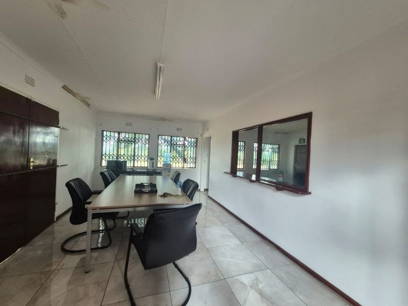 Office space featuring tiled flooring, security bars on windows, and an internal service window, showing signs of ceiling water damage.