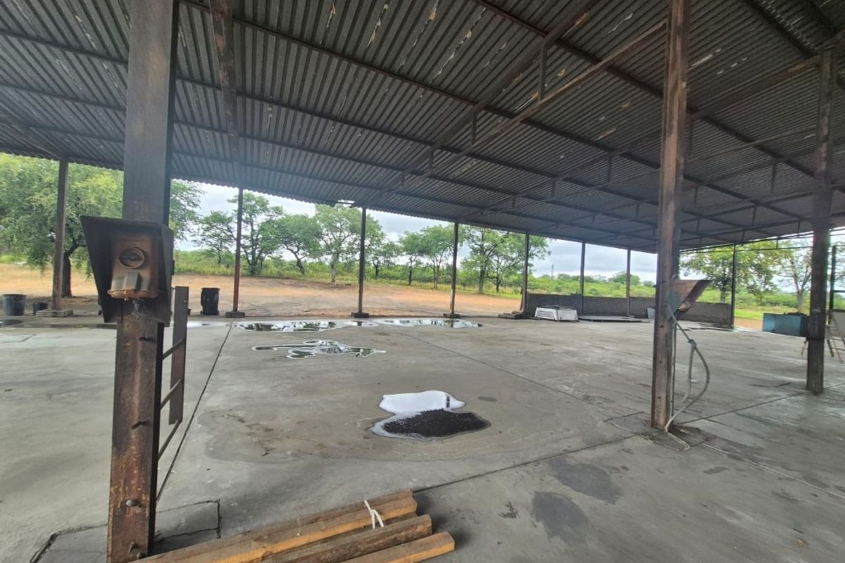 Large open-plan industrial utility space featuring a corrugated metal roof, steel support columns, and concrete flooring, suitable for storage or workshop operations.