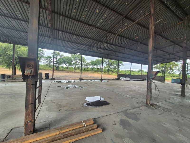 Large open-plan industrial utility space featuring a corrugated metal roof, steel support columns, and concrete flooring, suitable for storage or workshop operations.