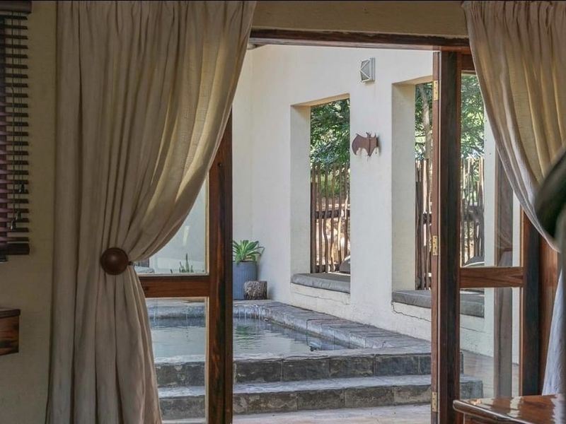 A view from the interior looking out onto a private patio area featuring a stone-clad plunge pool and built-in bench seating.