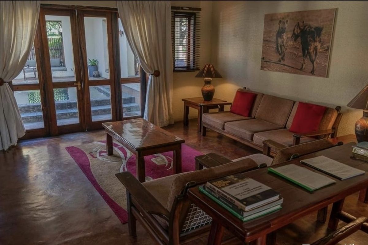 A comfortable living room featuring polished concrete floors and large wooden-framed glass doors that provide direct access to an outdoor patio area.