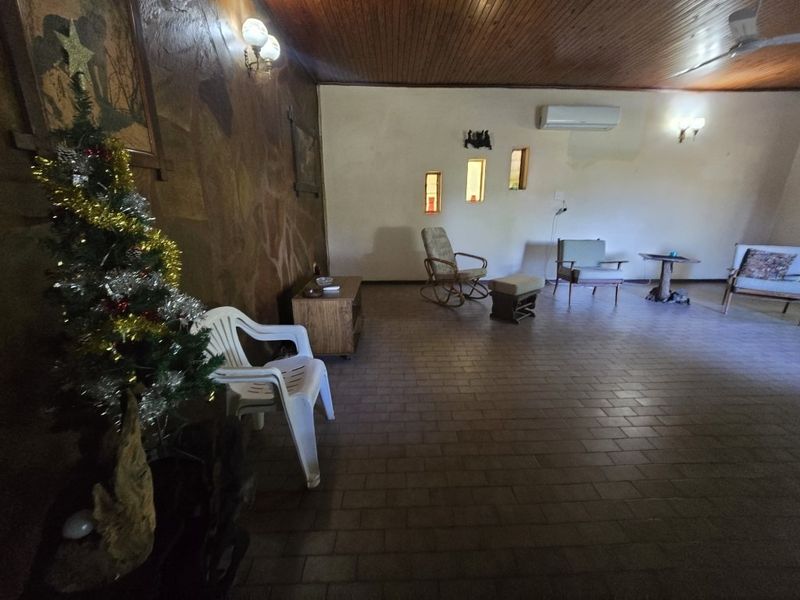 Spacious living area featuring a timber-clad ceiling, stone feature wall, tiled flooring, and a wall-mounted air conditioning unit.