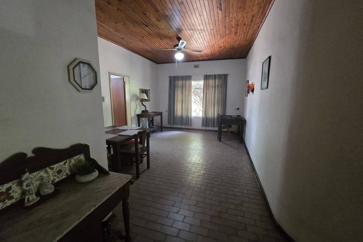 Spacious living area featuring a warm timber tongue and groove ceiling, tiled flooring, and a central ceiling fan.