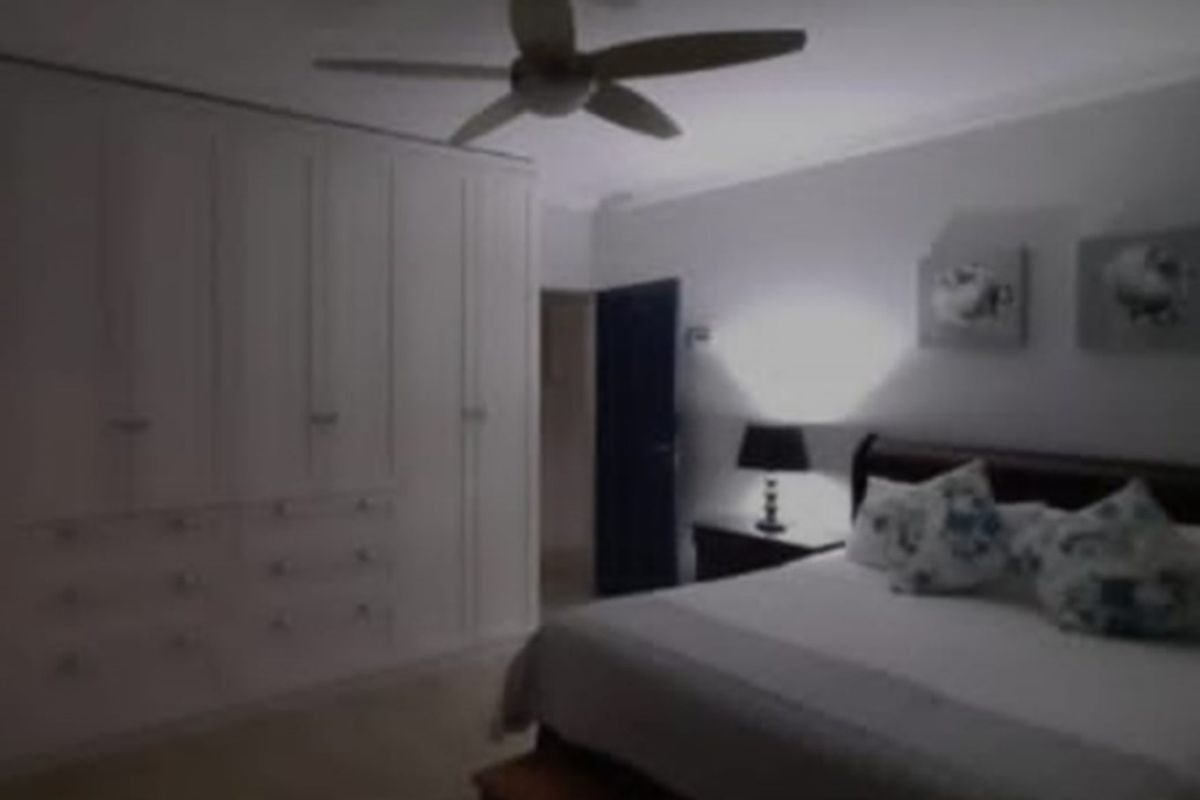A bedroom featuring built-in floor-to-ceiling cabinetry and a ceiling fan, providing ample storage and climate control.