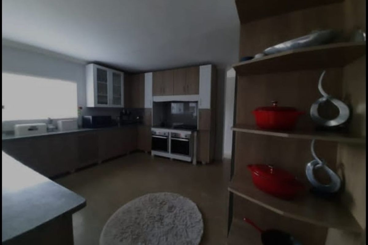 A functional kitchen featuring built-in cabinetry, a double oven, and a hob, with an open-plan layout connecting to the living area.