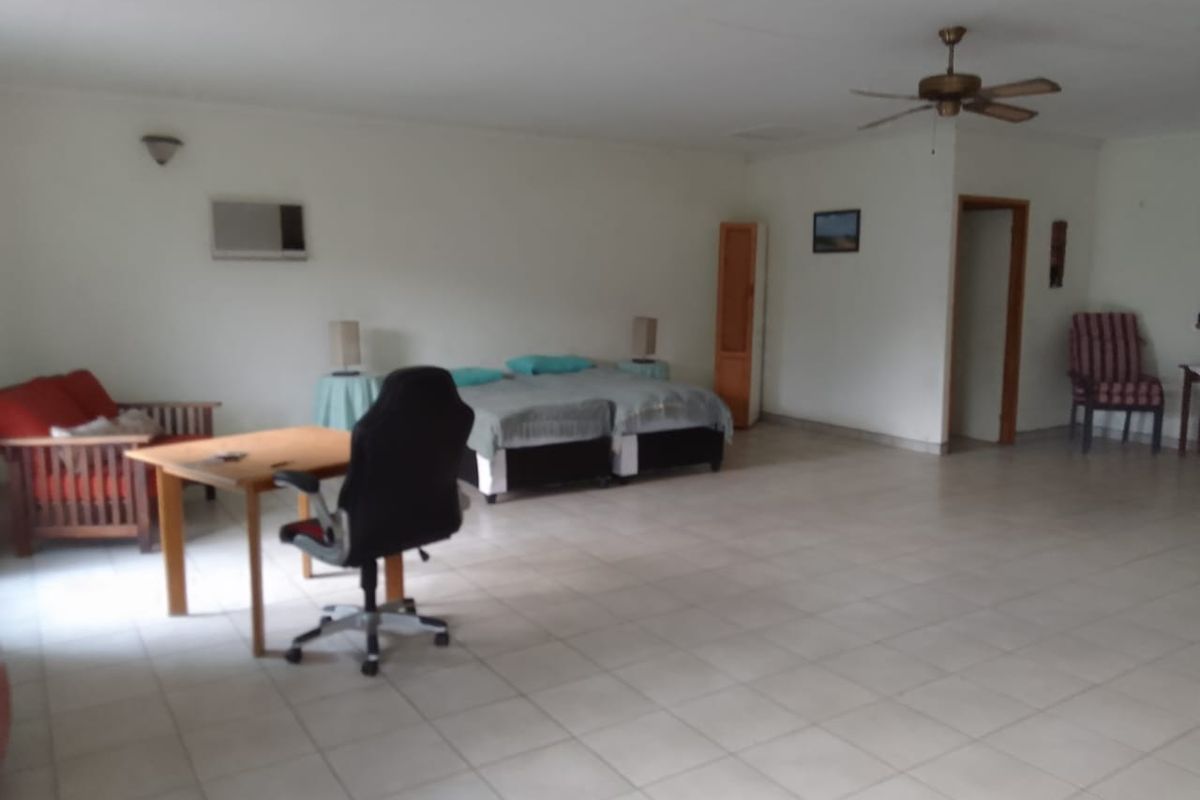Spacious bedroom featuring tiled flooring, a ceiling fan, and a wall-mounted air conditioning unit.