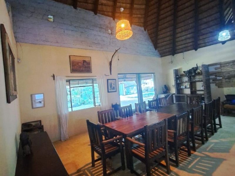 Spacious dining area featuring a high vaulted thatched roof with exposed rafters, built-in shelving, and large windows providing natural light.
