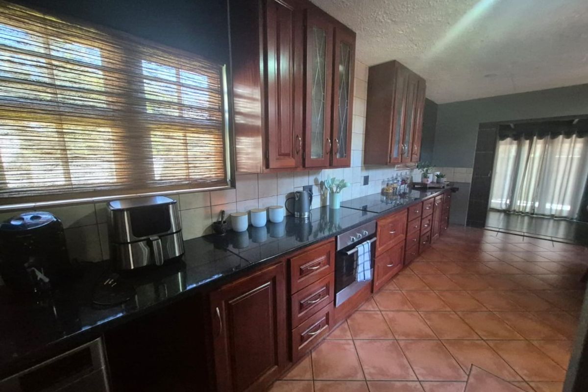 A functional kitchen featuring dark wood cabinetry, granite countertops, built-in oven, and ceramic tile flooring with a tiled backsplash.
