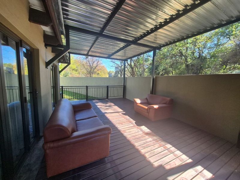 A covered outdoor patio featuring timber decking, a corrugated metal roof, and metal balustrades, providing a functional space for outdoor relaxation.