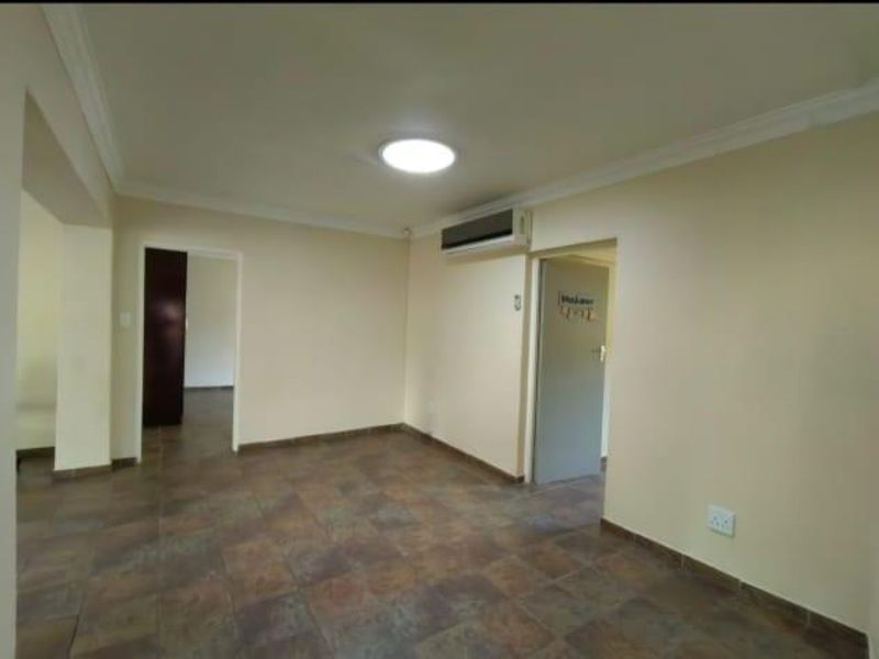An empty living room featuring tiled flooring, a split-system air conditioner, and neutral wall finishes.