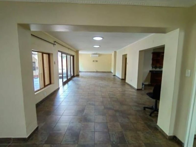 Spacious open-plan living area featuring tiled flooring, recessed lighting, and large sliding glass doors providing access to the exterior.