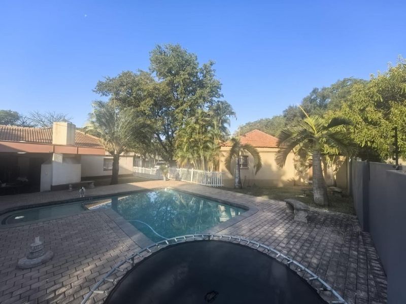 Outdoor pool area featuring a paved patio, swimming pool, and established garden surroundings, providing a private space for relaxation and entertainment.