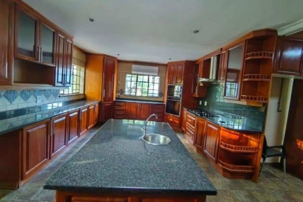 Spacious kitchen featuring extensive wooden cabinetry, granite countertops, a central island with a prep sink, and built-in appliances.