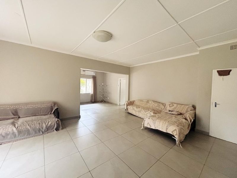 Spacious living area featuring neutral tiled flooring and a clean ceiling finish, offering a versatile layout for comfortable family living.