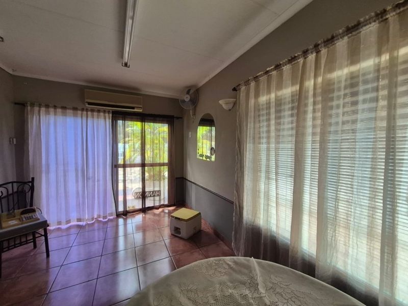 A living area featuring tiled flooring, a wall-mounted air conditioning unit, and sliding glass doors providing access to the exterior.