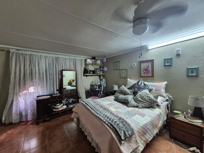 A bedroom featuring tiled flooring, a ceiling fan, and a wall-mounted air conditioning unit.