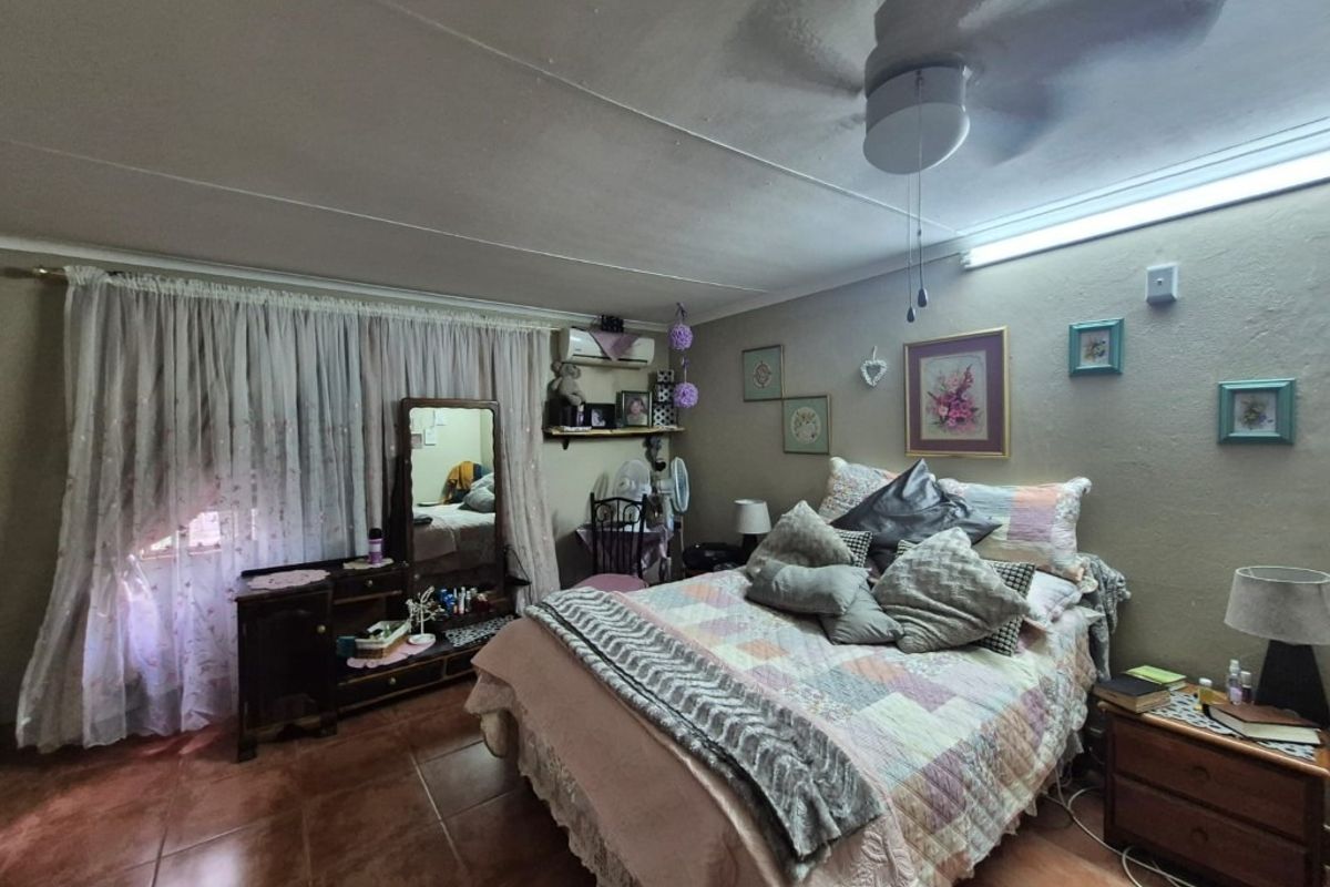 A bedroom featuring tiled flooring, a ceiling fan, and a wall-mounted air conditioning unit.