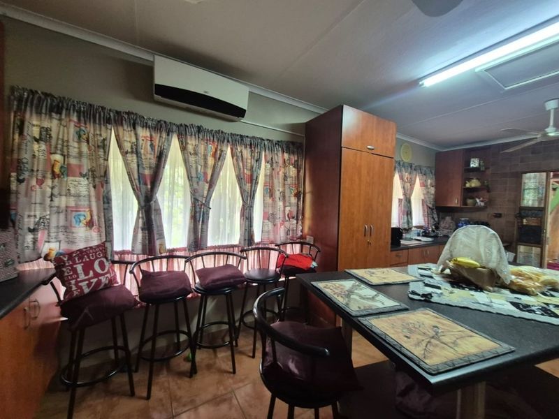 Open-plan kitchen and dining area featuring tiled flooring, built-in cabinetry, and a wall-mounted air conditioning unit.