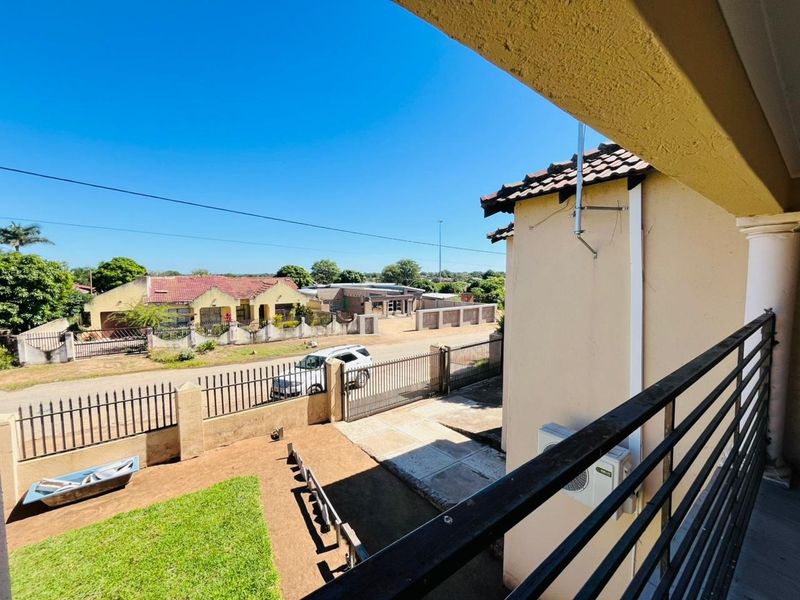 Elevated balcony view overlooking the front yard, driveway, and surrounding residential street.