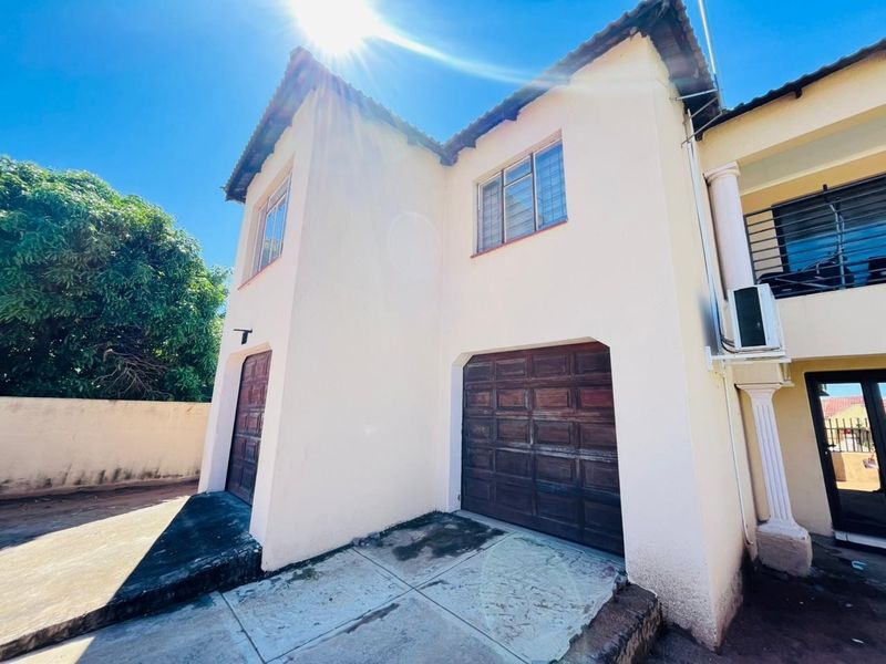 Front exterior view of the property featuring a double garage, concrete driveway, and tiled roof structure under a clear sky.