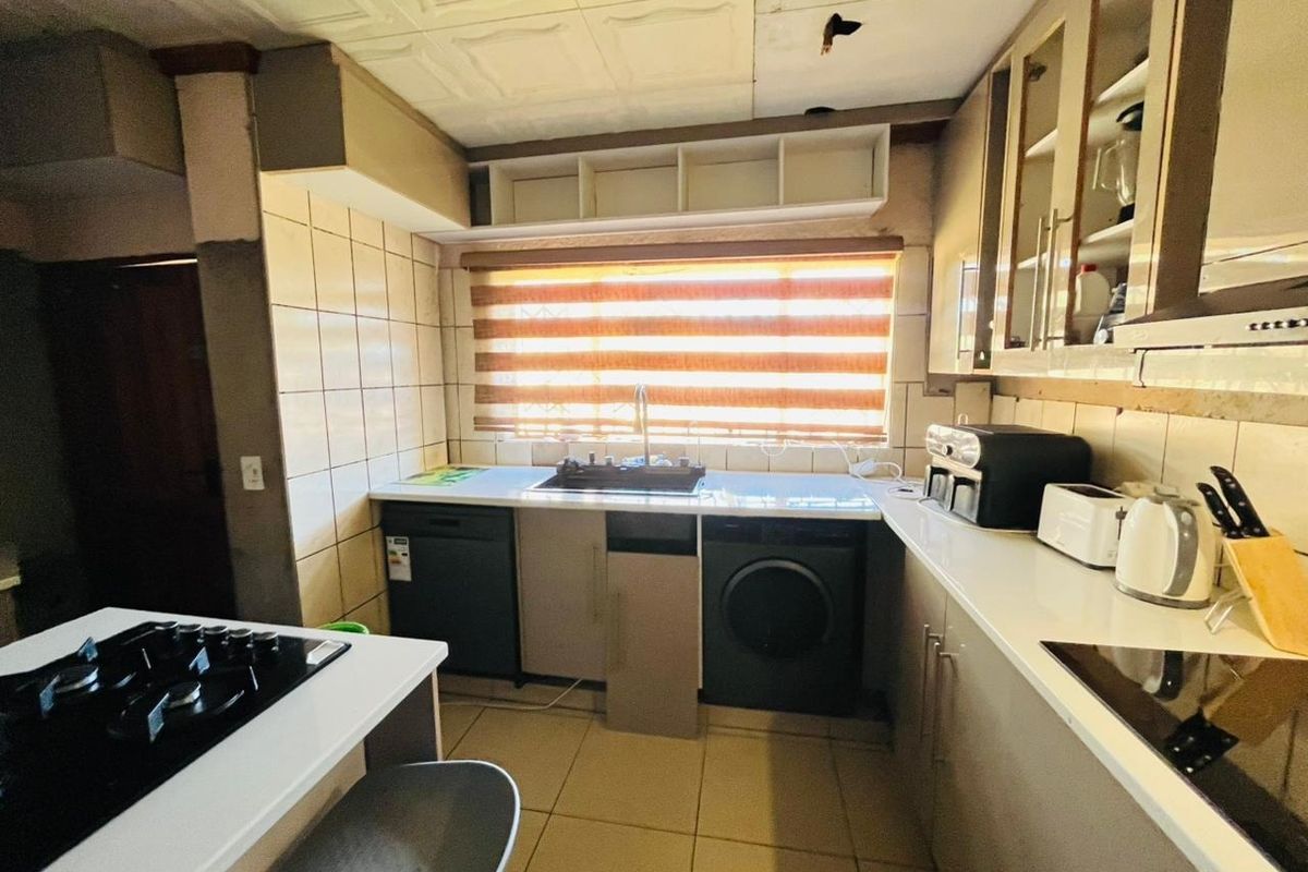 A functional kitchen featuring built-in cabinetry, stone countertops, and a tiled backsplash, currently requiring some ceiling and cabinetry repairs to improve its overall condition.