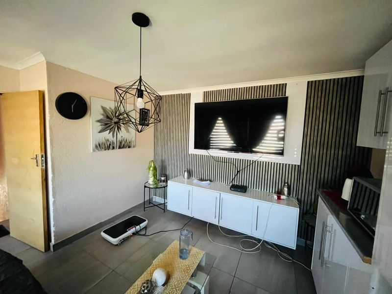 A living area featuring modern slatted wall paneling, tiled flooring, and a contemporary pendant light fixture.