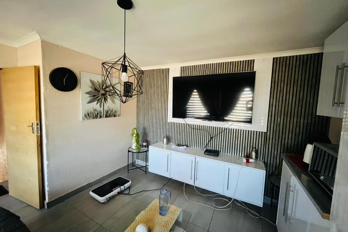 A living area featuring modern slatted wall paneling, tiled flooring, and a contemporary pendant light fixture.