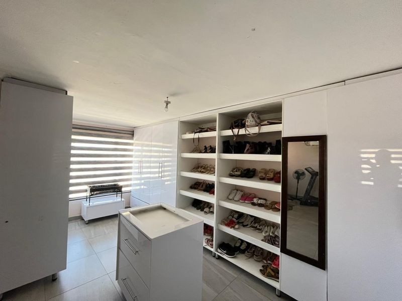A walk-in closet or dressing room featuring extensive built-in cabinetry, open shelving for storage, and tiled flooring with natural light from the window.