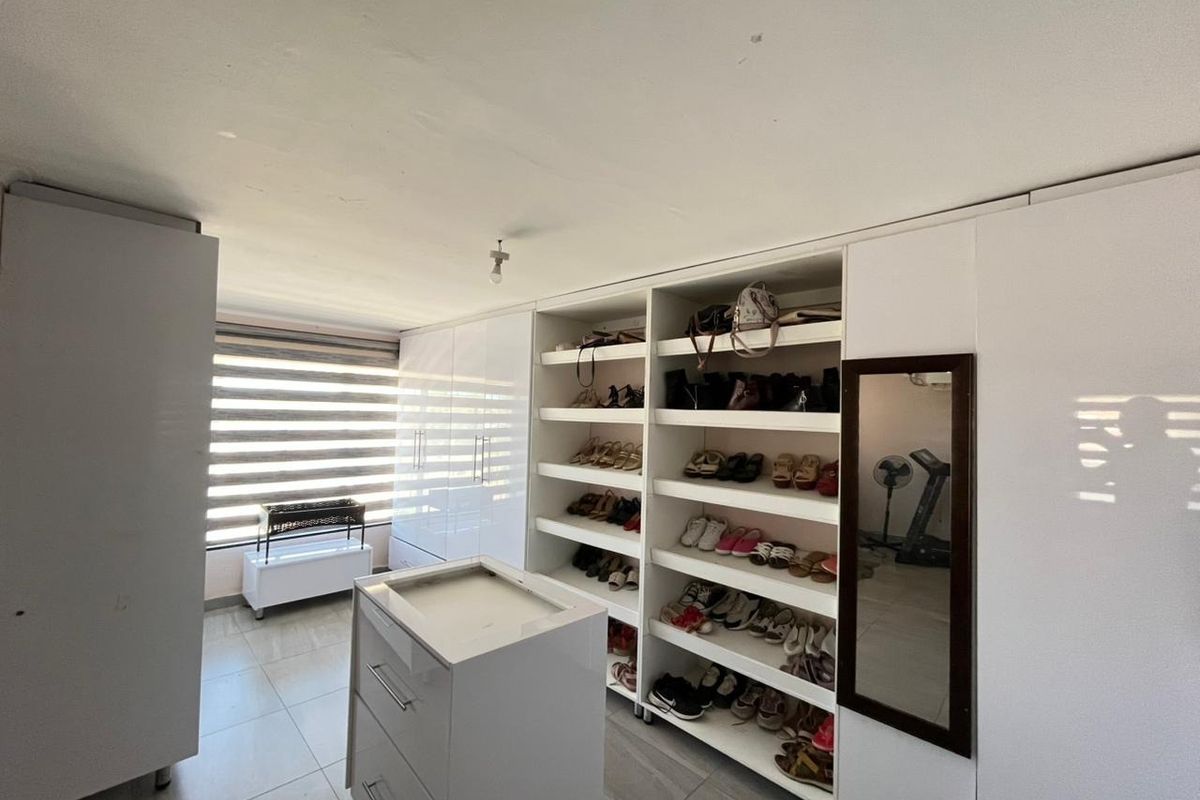 A walk-in closet or dressing room featuring extensive built-in cabinetry, open shelving for storage, and tiled flooring with natural light from the window.