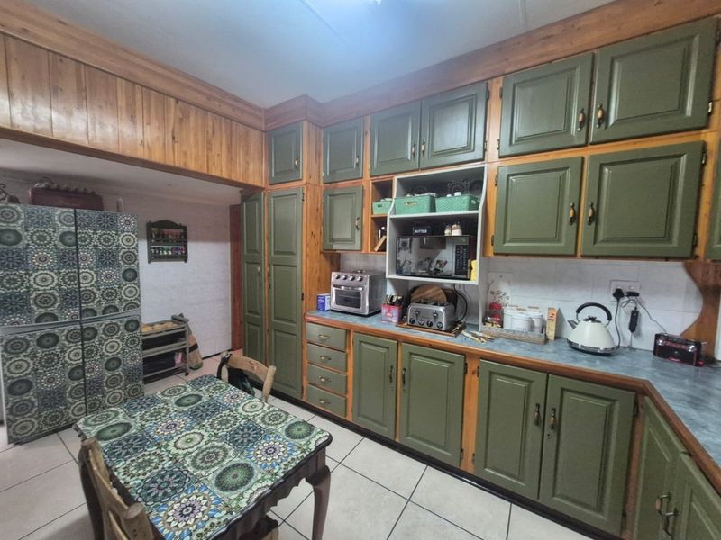 A functional kitchen featuring extensive built-in wooden cabinetry, tiled flooring, and a tiled backsplash, offering a traditional aesthetic with ample storage space.