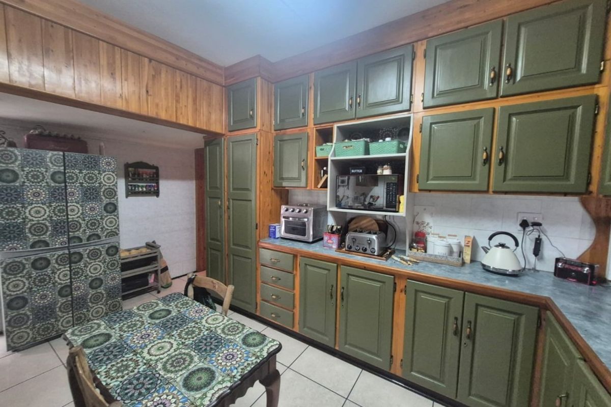 A functional kitchen featuring extensive built-in wooden cabinetry, tiled flooring, and a tiled backsplash, offering a traditional aesthetic with ample storage space.