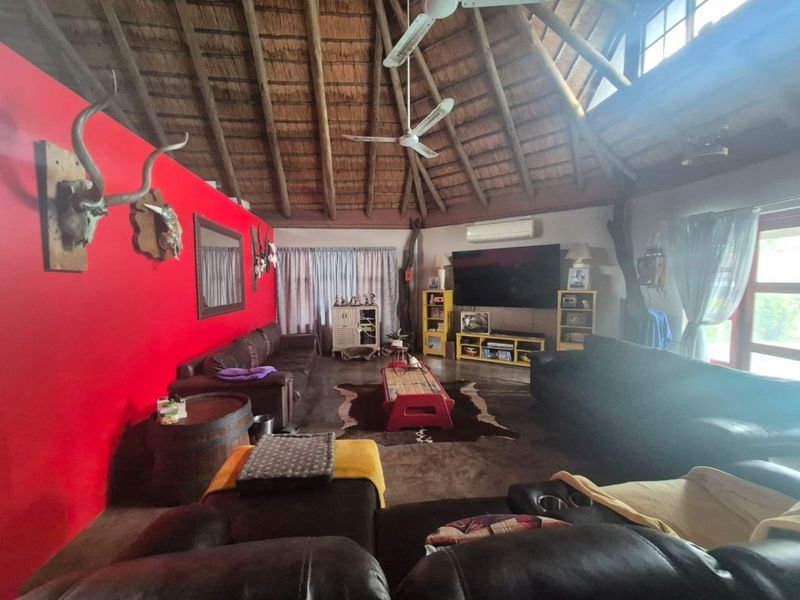 Spacious living room featuring a high vaulted thatched ceiling with exposed timber rafters, ceiling fans, and a wall-mounted air conditioning unit.