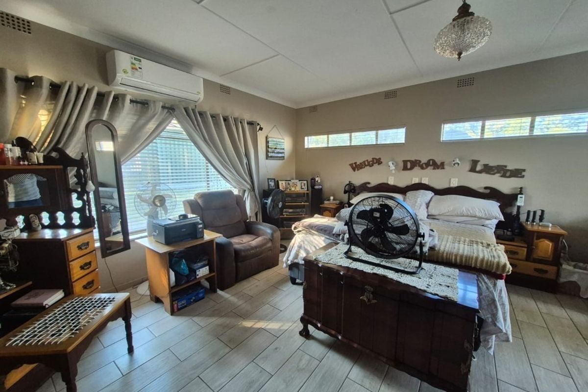Spacious bedroom featuring tiled flooring, a wall-mounted air conditioning unit, and clerestory windows providing natural light.