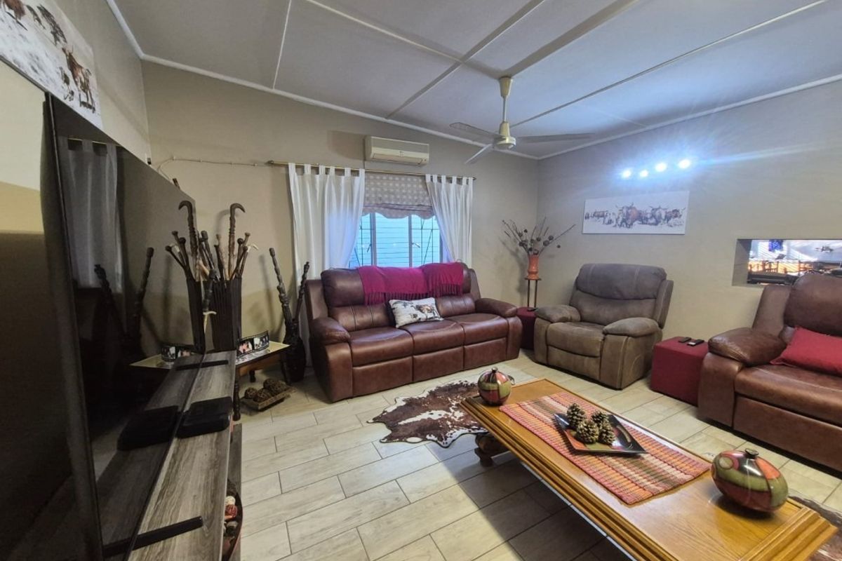 A comfortable living room featuring tiled flooring, a ceiling fan, and a wall-mounted air conditioning unit, providing a functional and relaxed living space.