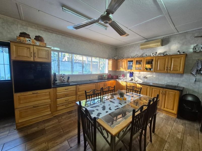 Spacious kitchen featuring extensive wooden cabinetry, built-in oven, hob, and tiled finishes, offering a functional layout with ample storage and workspace.