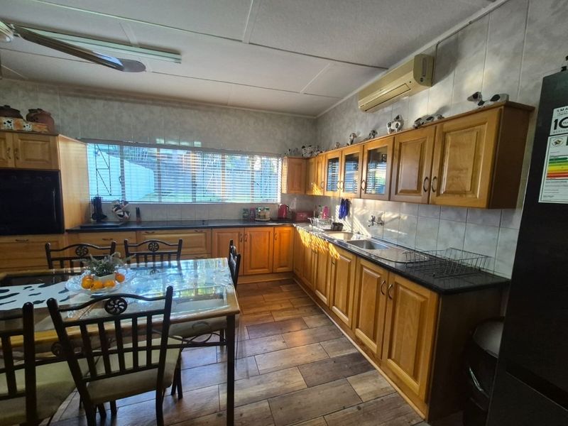 A functional kitchen featuring wooden cabinetry, laminate countertops, a double sink, and tiled flooring, offering a traditional layout with ample storage space.