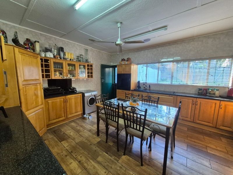 Spacious kitchen featuring wooden cabinetry, granite countertops, built-in oven, and tiled flooring, with an integrated dining area and ceiling fan.