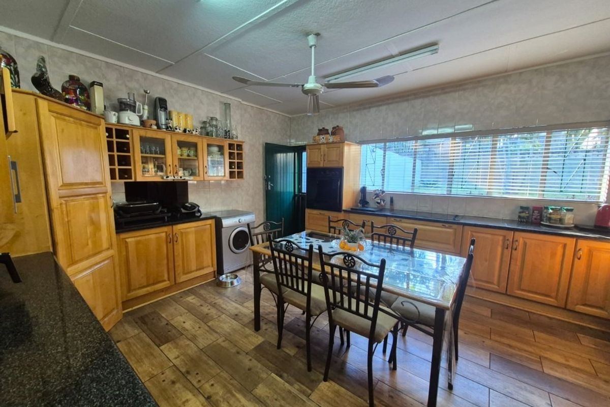 Spacious kitchen featuring wooden cabinetry, granite countertops, built-in oven, and tiled flooring, with an integrated dining area and ceiling fan.
