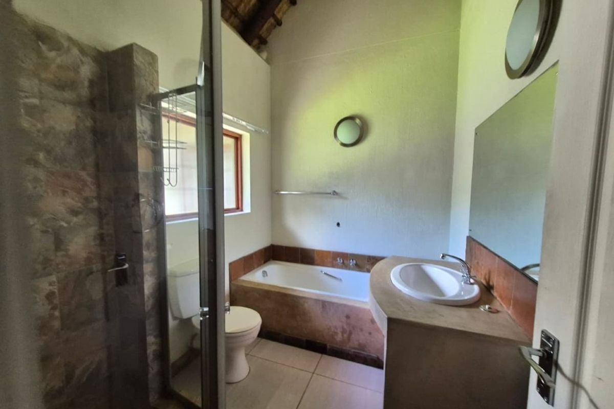 A bathroom featuring a shower enclosure, built-in bathtub, vanity basin, and toilet, set under a high vaulted ceiling with tiled finishes.
