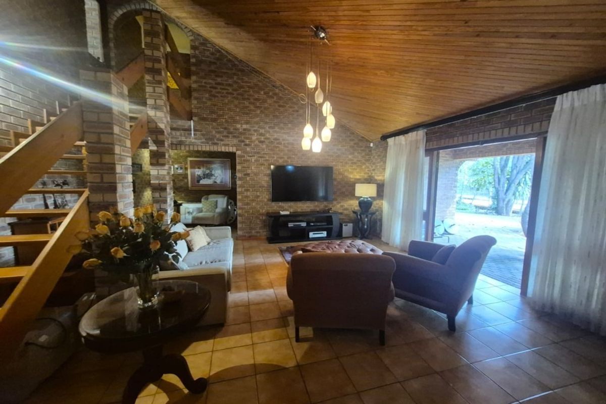 Spacious living room featuring exposed brick walls, a high timber vaulted ceiling, tiled flooring, and direct access to the outdoor patio area.