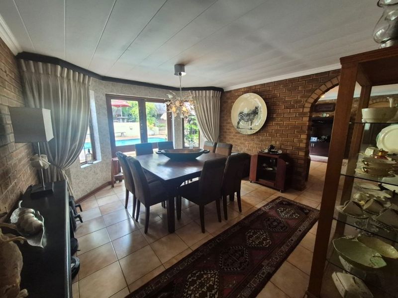Dining room featuring exposed brick walls, tiled flooring, and direct access to the outdoor pool area through timber-framed glass doors.