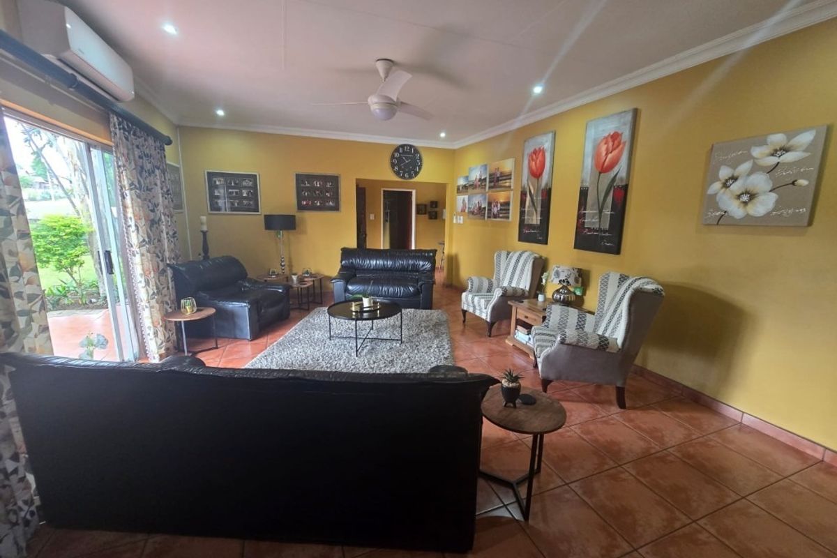 Spacious living room featuring tiled flooring, a ceiling fan, split-system air conditioning, and large sliding glass doors providing access to the outdoor area.